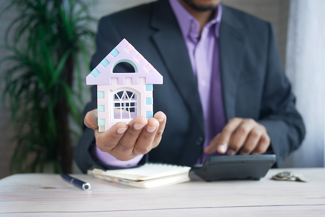 Person in a suit holding their hand out with a small replica of a house